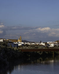 Buildings by river against sky in city