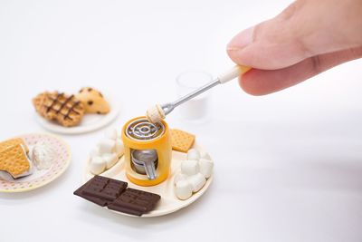 Midsection of person holding ice cream against white background