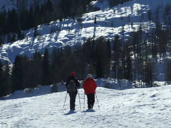 Rear view of people walking on snow covered mountain