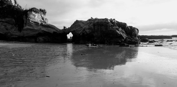 Rock formations on beach against sky