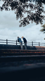 People standing on bridge against sky