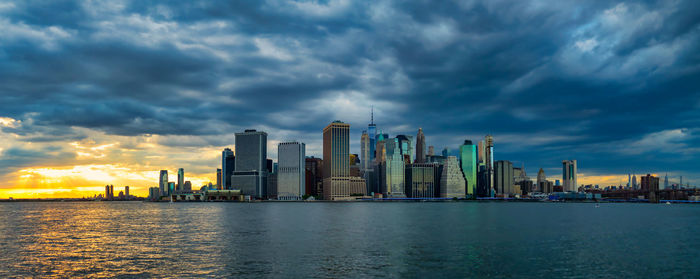 Sea by modern buildings against sky in city