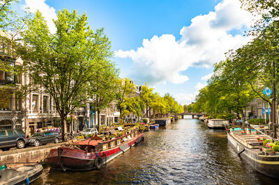 Boats moored in canal against sky in city