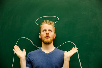 Smiling young man with halo drawing on blackboard