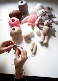 Cropped hand of woman knitting by teddy bears at table