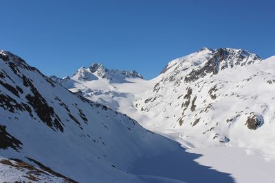 Scenic view of snowcapped mountains against clear blue sky