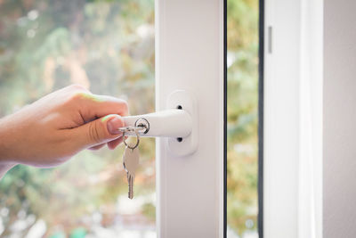 Close-up of hand holding handle of window