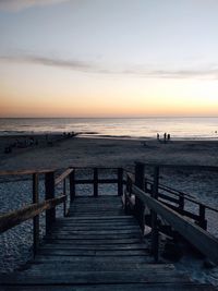 Pier over sea against sky during sunset