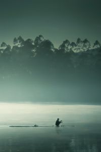 Silhouette fishing rod on sea against sky