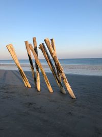 Wooden posts on beach against clear sky