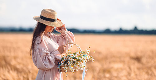 Midsection of woman wearing hat standing on field