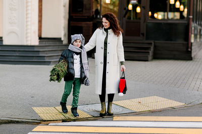 A beautiful mother and her son are walking out of the store, holding a bag of gifts 