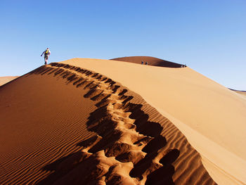 Low angle view of man on sand dune against clear sky