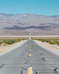 Road leading towards mountains against sky