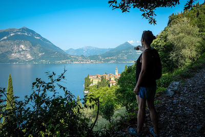 Rear view of woman looking at lake against mountain