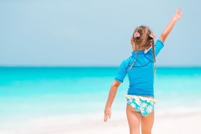 Rear view of woman standing at beach against sky