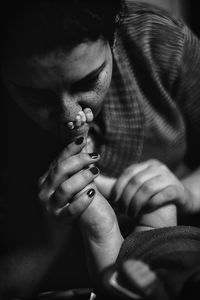 Close-up of mother kissing on baby barefoot in darkroom