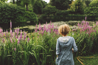 Rear view of woman standing by plants at park