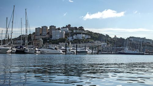 Boats moored at harbor against sky