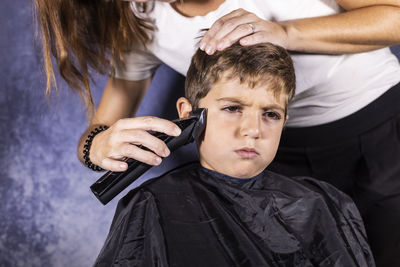 Woman cutting hair against wall