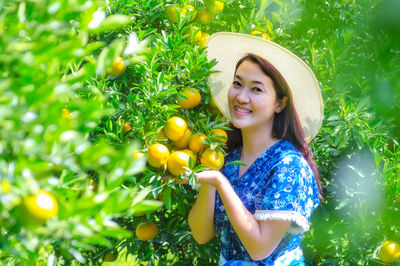 Portrait of a smiling young woman standing by plants