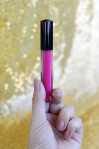 Close-up of woman holding pink lipstick