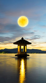 Built structure in lake against sky during sunset