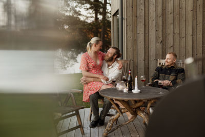 Couple with friend sitting on patio and drinking wine