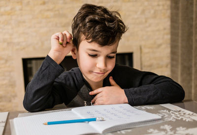 Cheerful and funny schoolboy solves  homework emotionally. thinks about how to solve math examples 