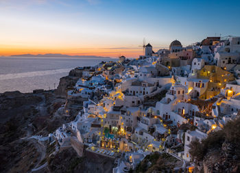 High angle view of townscape by sea against sky during sunset