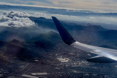 Airplane flying over landscape against sky