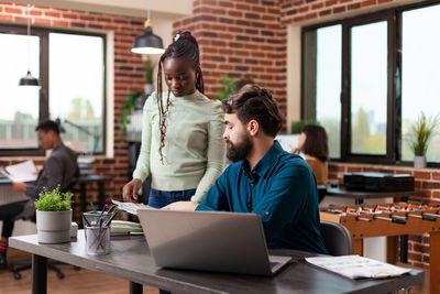 Female colleague standing by coworker at office