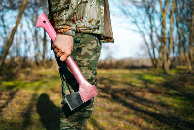 Low section of person holding pink axe in the forest