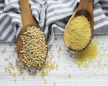 Raw couscous in a wooden spoons on the table