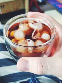 Close-up of hand holding drink on table