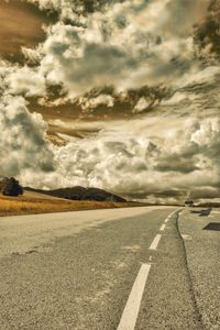 Road passing through landscape against cloudy sky