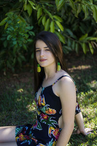 Portrait of beautiful young woman sitting against plants