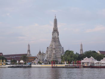 View of buildings by river against sky