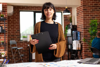 Portrait of young woman using digital tablet at office