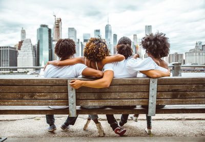 Rear view of friends looking at cityscape by river