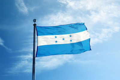 Low angle view of flag against blue sky