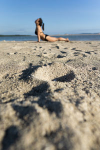 Surface level of woman on beach against sky