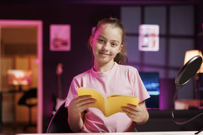 Portrait of young woman using mobile phone while sitting on table