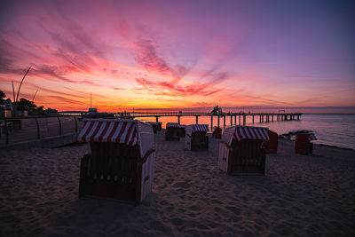 Chairs on beach against sky during sunset