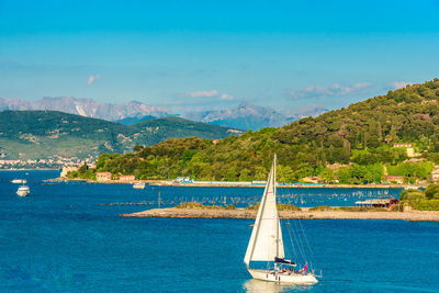 Sailboat sailing in sea against blue sky