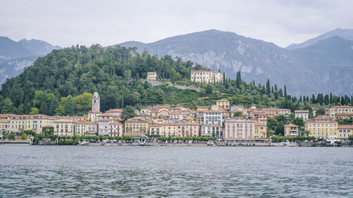 Buildings by sea against mountain range