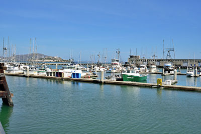 Sailboats moored at harbor against blue sky