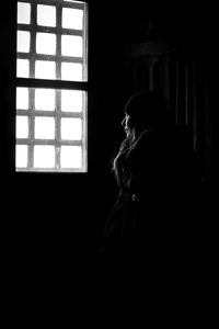 Woman looking through window in darkroom