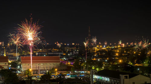 Firework display in city against sky at night