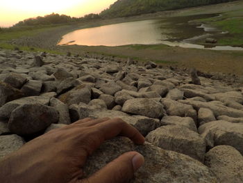 Close-up of hand holding pebbles at beach against sky